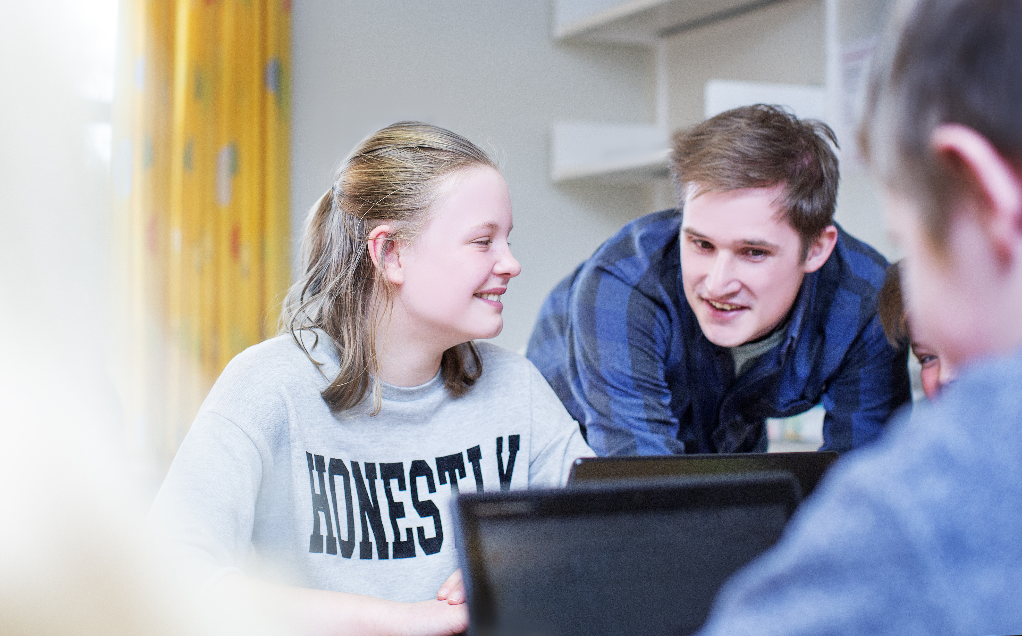 Mannlig lærerstudent står ved siden av elev i klasserom