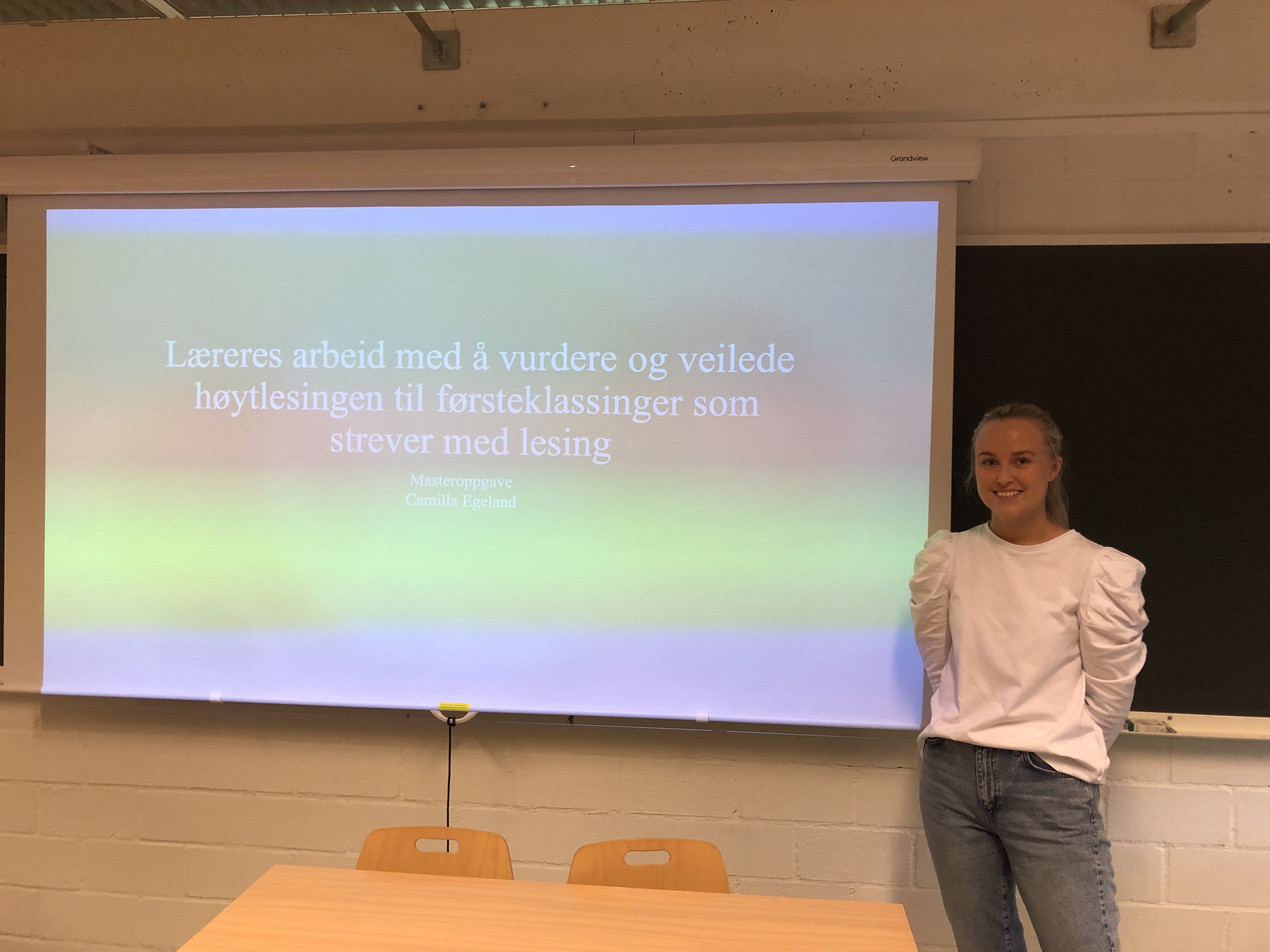 Kvinne i hvit bluse står foran smartboard