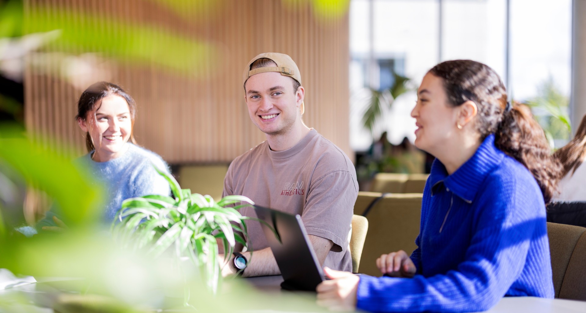 Tre studenter sitter sammen ved et arbeidsbord