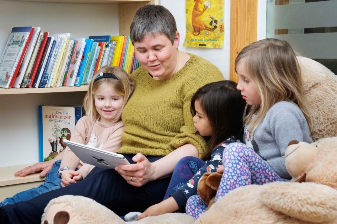 Barn leser på iPad sammen med barnehagelærer