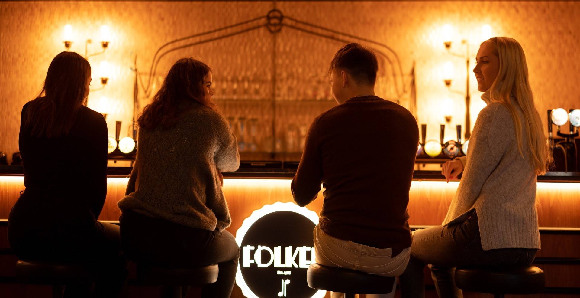 Fire mennesker sitter ved en bar.