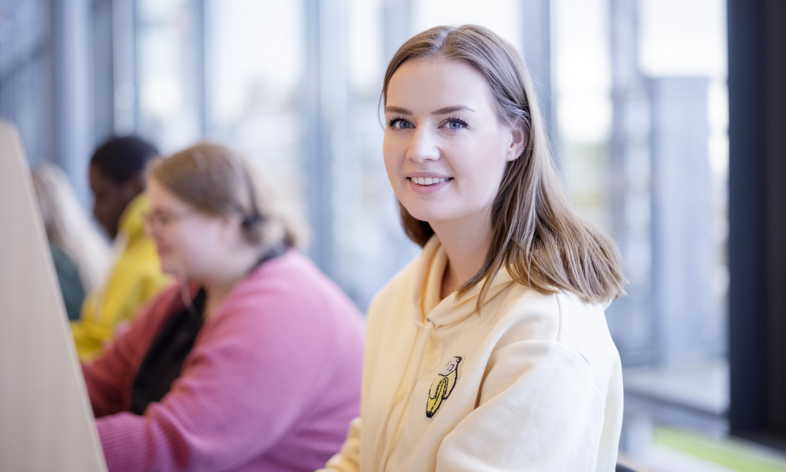 Kvinnelig student på lesesal smiler til kameraet