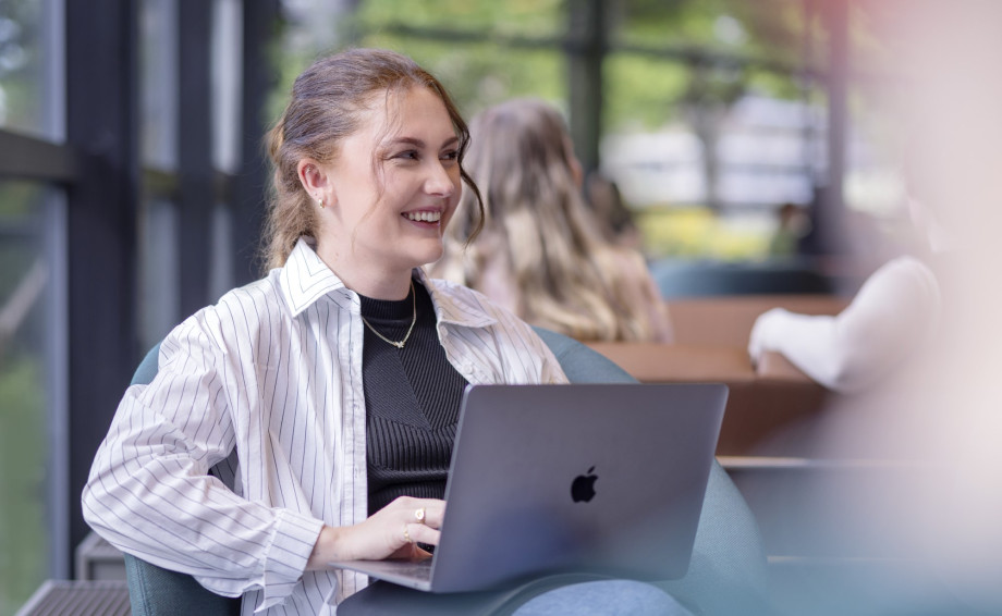 Student holder en pc og smiler